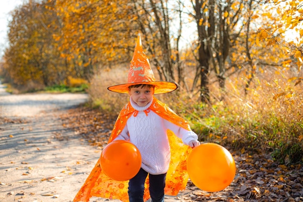 Portret van een jongen in Halloween-kleding met pompoenballonnen op straat Een traditionele feestdag 31 oktober