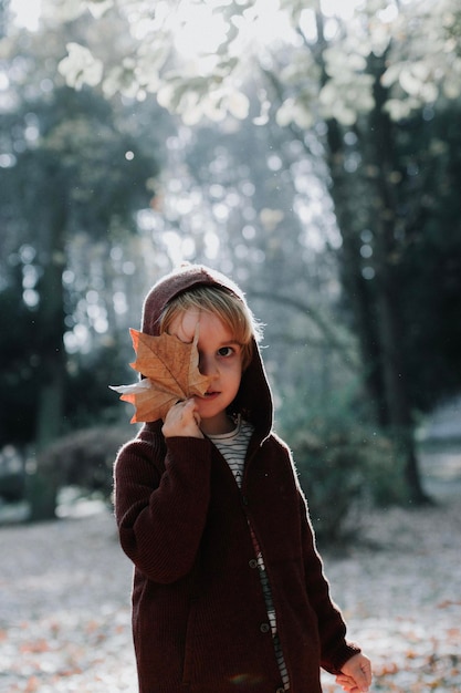 Portret van een jongen met een blad dat in de herfst op het veld staat