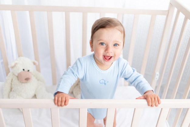 Portret van een jongetje in een wieg in een kinderkamer met grote blauwe ogen