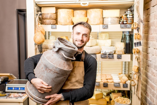 Portret van een kaasverkoper met een grote zuivelemmer die in de kaaswinkel staat