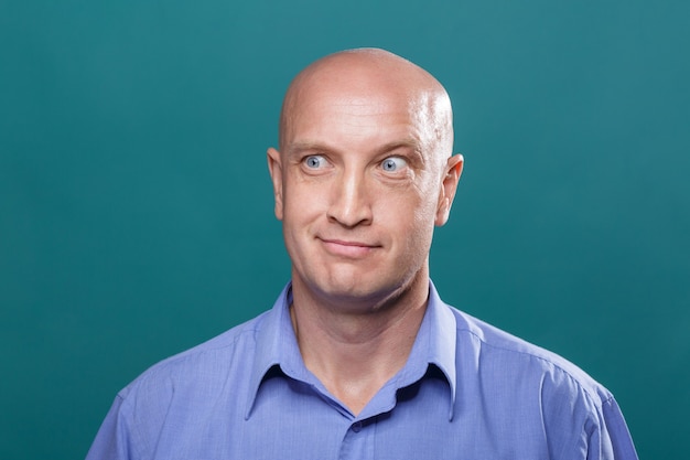 Foto portret van een kale man op een blauwe achtergrond model in haar blauwe ogen en een blauw shirt met lachend gezicht...