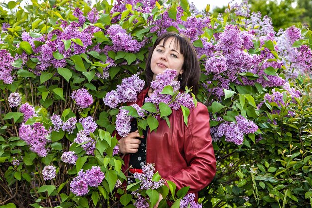 Foto portret van een kalme mooie vrouw tussen de bloesems van een bloeiende sering voor een wandeling in het park.