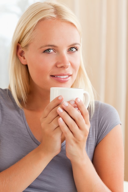 Portret van een kalme vrouw, zittend op een bank met een kopje thee