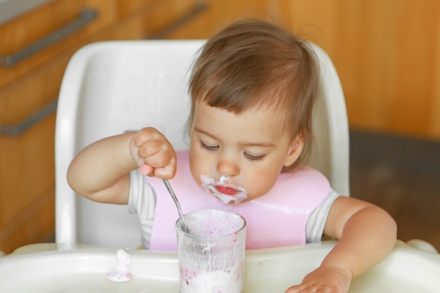 Portret van een kind dat babyvoeding met zijn lepel eet. mijn gezicht is besmeurd met voedsel