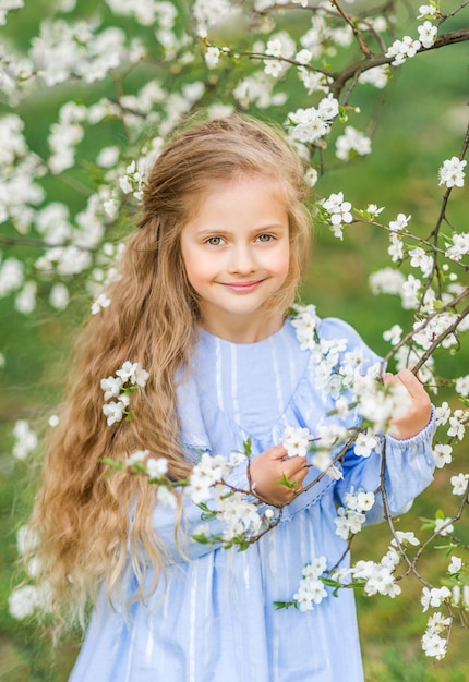 Portret van een kind meisje in een bloeiende tuin. Lente foto. Bloemen in je haar