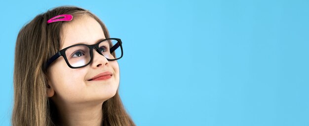 Portret van een kind schoolmeisje close-up kijken bril geïsoleerd op blauw oppervlak dragen