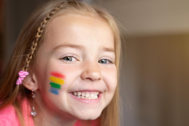 Portret van een kind uit een lgbt-familie met een regenboogvlag op zijn wang voor pride day