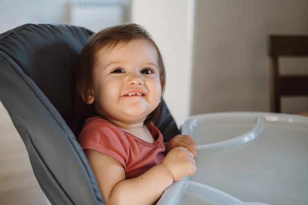 Portret van een klein babymeisje glimlachend zittend in een kinderstoel mooi meisje babyverzorging