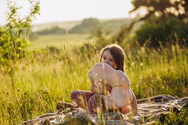 Portret van een klein babymeisje zittend op een plaid op picknick buiten bij zonsondergang