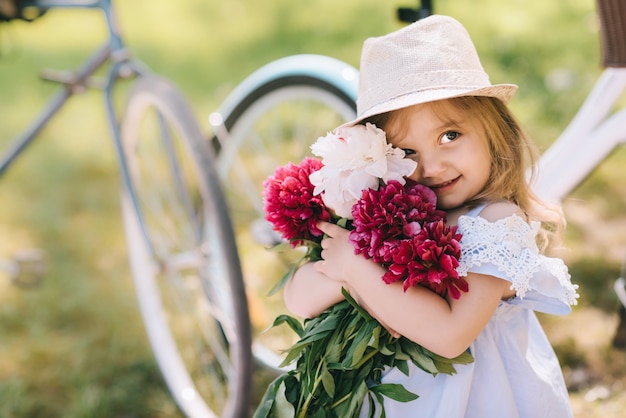 Portret van een klein glimlachend meisje met groot boeket van bloemen op te groene backgroud