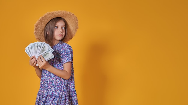 Portret van een klein kaukasisch meisje met lang haar in zomerjurk houdt veel geld geïsoleerd op je...