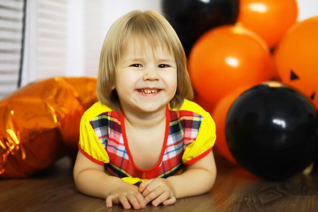 Portret van een klein kind dat op de vloer ligt in een kamer versierd met ballonnen Gelukkig jeugdconcept