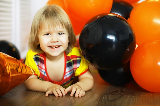 Portret van een klein kind dat op de vloer ligt in een kamer versierd met ballonnen Gelukkig jeugdconcept