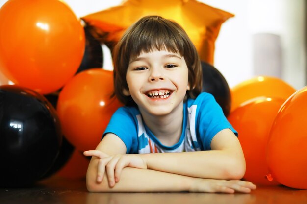 Portret van een klein kind dat op de vloer ligt in een kamer versierd met ballonnen. Gelukkig kindertijdconcept.