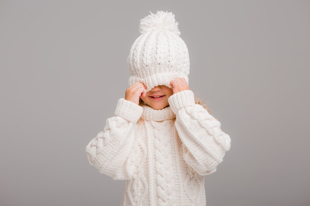 Portret van een klein krullend-haired meisje in een gebreide witte de winterhoed