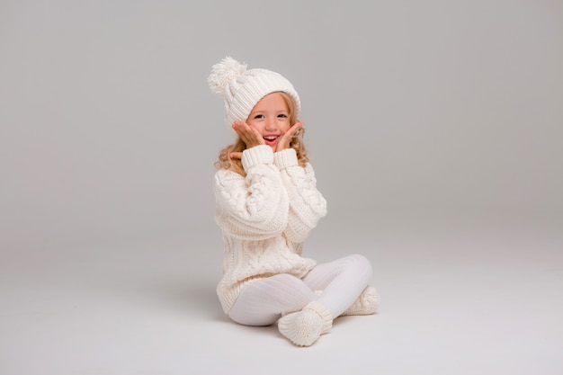 Portret van een klein krullend-haired meisje in een gebreide witte de winterhoed