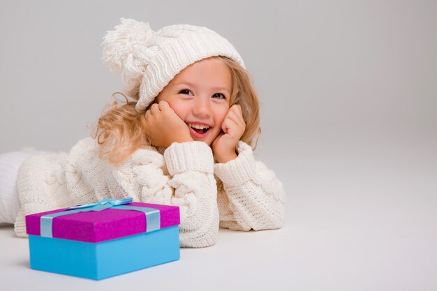 Portret van een klein krullend-haired meisje in een gebreide witte de winterhoed