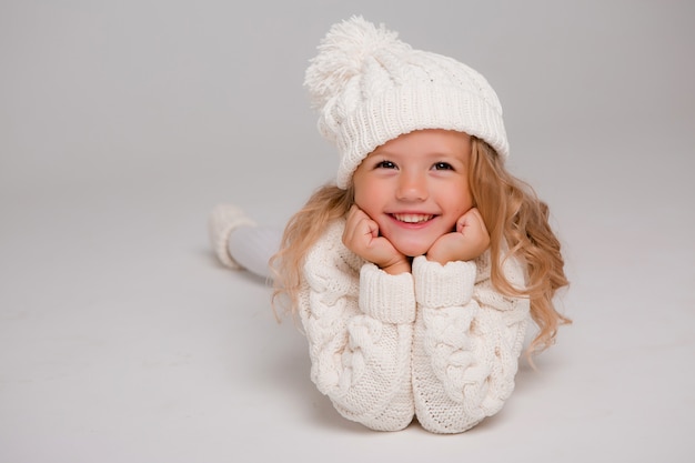 Portret van een klein krullend-haired meisje in een gebreide witte de winterhoed