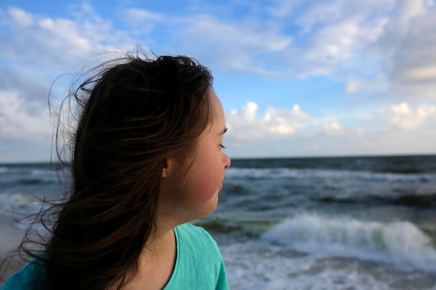 Portret van een klein meisje dat lacht op de achtergrond van de zee