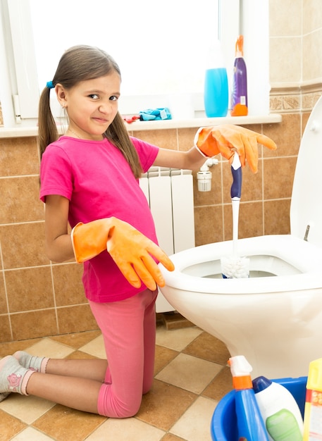 Portret van een klein meisje dat toilet met afschuw schoonmaakt