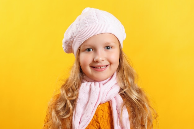 Portret van een klein meisje in een baret en een sjaal op de achtergrond.