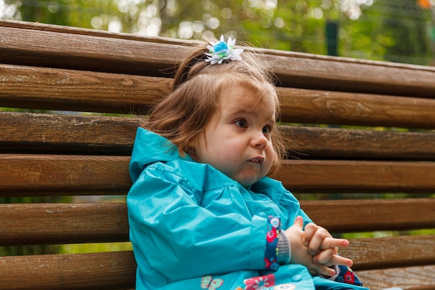 Portret van een klein meisje in het park op een bankje vangt zeepbellen