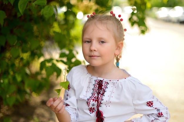 Portret van een klein meisje met bloemen in een Oekraïens geborduurd hemd Viburnum in haar