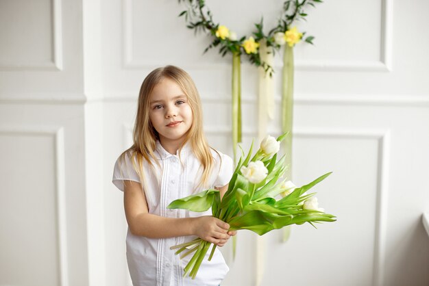 Portret van een klein meisje met een boeket van witte tulpen.