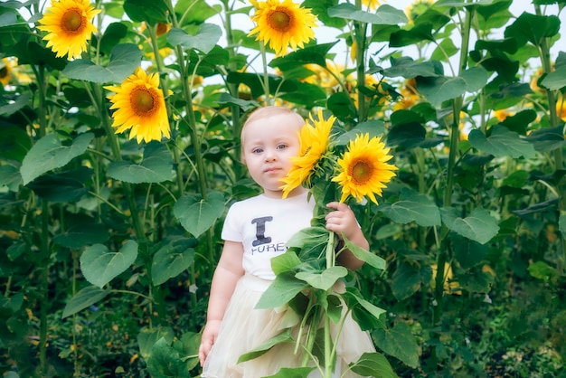 portret van een klein meisje met een boeket zonnebloemen in haar linkerhand