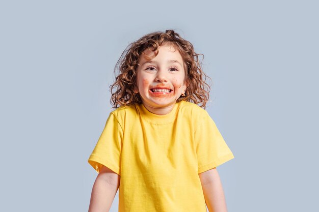 Portret van een klein meisje met een vuile mond Schattig klein meisje met krullend haar besmet met chocoladecrème