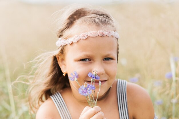 Portret van een klein meisje met korenbloemen. zomervakantie concept.