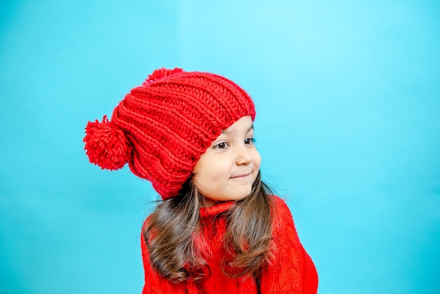 portret van een klein meisje met krullend haar in een gebreide rode muts in de winter klein meisje met donker haar