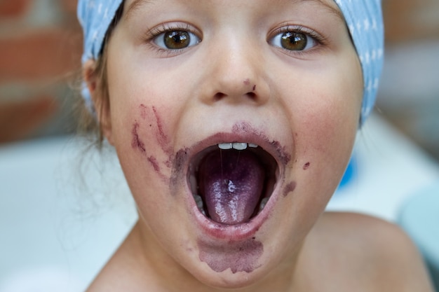 Portret van een klein meisje met open mond na het eten van moerbeiboombessen