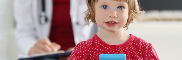 Portret van een klein meisje op de achtergrond van arts in witte jas. Kinderonderzoek en medische zorgconcept