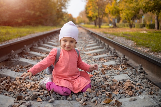 portret van een klein meisje zittend op de treinrails in het bos