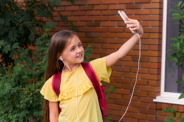 Portret van een klein mooi meisje met behulp van een mobiele telefoon en het nemen van een selfie