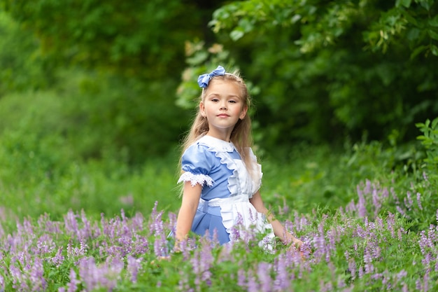 Portret van een klein schattig meisje verkleed als Alice. Gestileerde fotoshoot in de natuur.