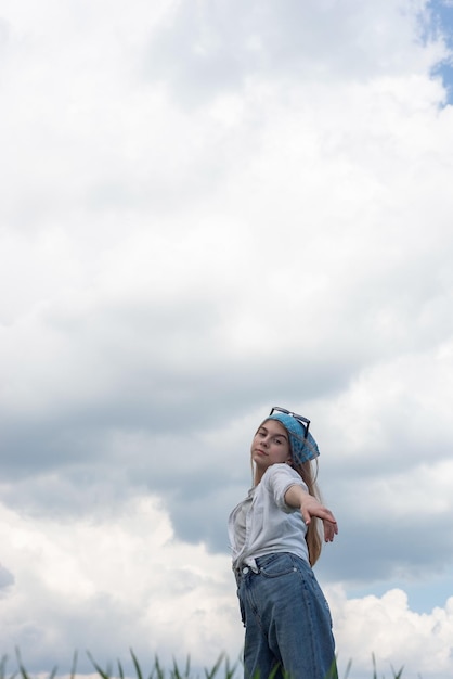 Portret van een klein tienermeisje in een bandana tegen de achtergrond van een bewolkte hemel