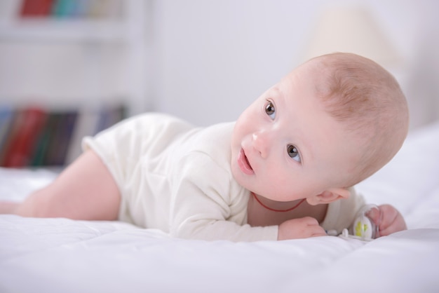 Portret van een kleine baby die op bed speelt.