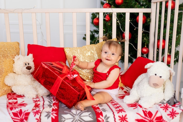 Portret van een kleine baby in een wieg thuis bij de kerstboom