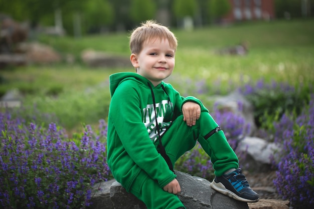 Portret van een kleine glimlachende jongen op de achtergrond van een bloeiend park