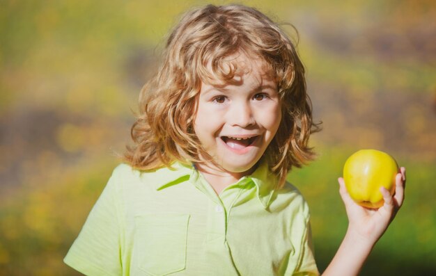 Portret van een kleine jongen die een appel vasthoudt en eet over groene natuurachtergrond