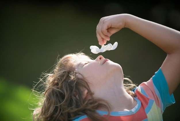 Portret van een kleine jongen die een plumeria-bloem ruikt