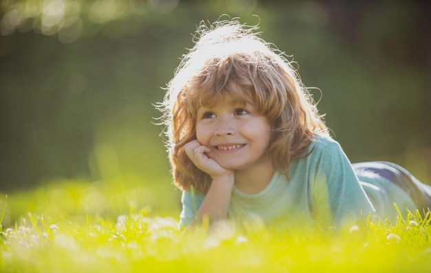 Portret van een kleine jongen die op gras ligt in het zomernatuurpark