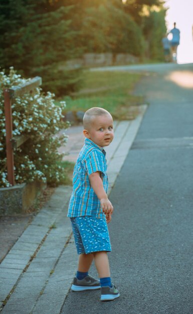 Portret van een kleine jongen die op het voetpad loopt