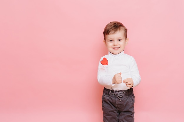 portret van een kleine jongen met een hartvormige lolly in zijn hand.