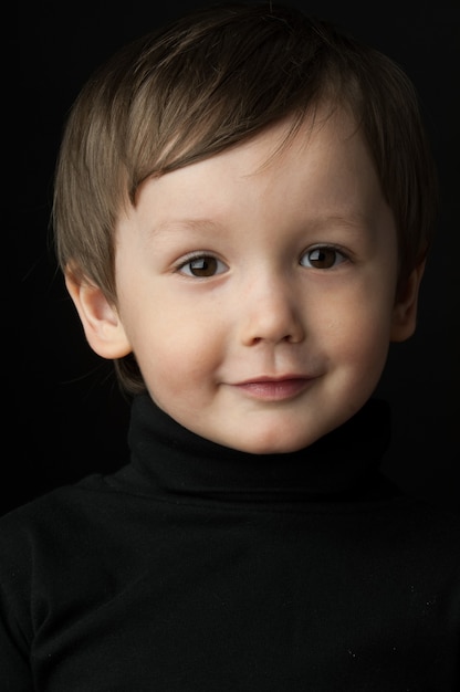 Portret van een kleine jongen op een donkere achtergrond