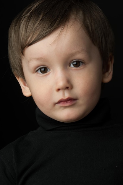 Portret van een kleine jongen op een donkere achtergrond