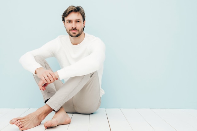 Portret van een knap glimlachend hipster-houtseksueel zakenmanmodel met een casual witte trui en broek