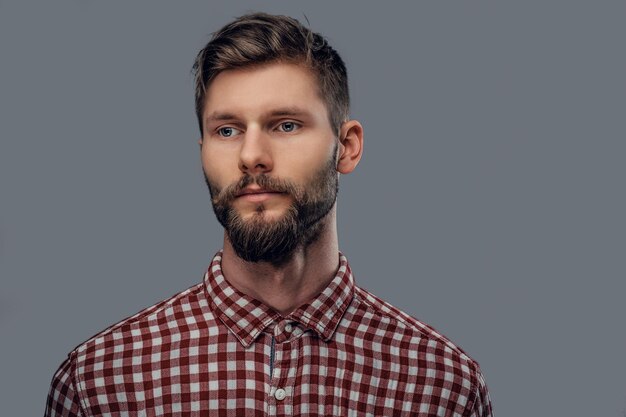 Portret van een knappe bebaarde hipster man gekleed in een fleece shirt geïsoleerd op een grijze achtergrond.